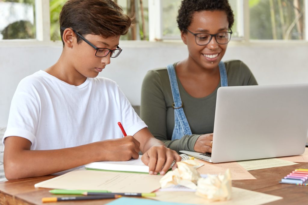 Children's working on their assignment while using a laptop.